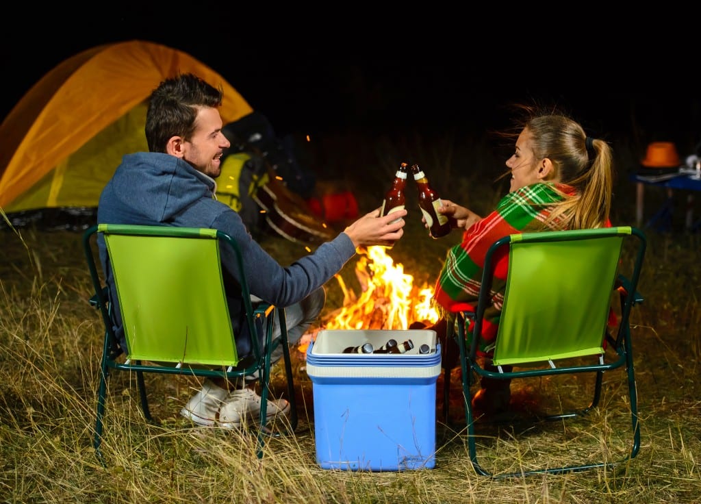 Romantic evening. Couple campfire while camping drinking beer