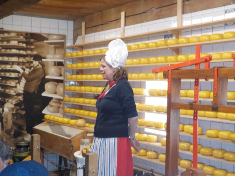 Dutch lady in traditional dress explaining the traditional cheese making process
